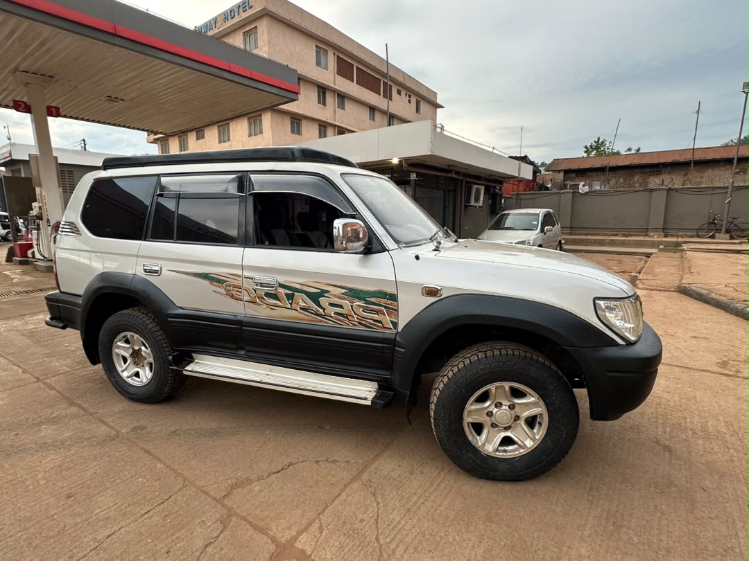 rav4 - Rent 4x4 Car Uganda White SUV with green and gold side graphics parked at a gas station, beige building and pump canopy in the background.